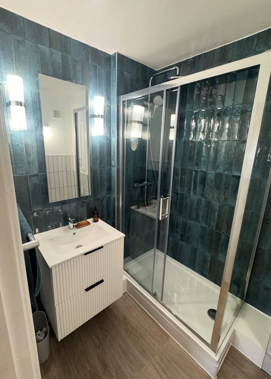 Completed teal-tiled shower room by Infinite Plumbing & Heating