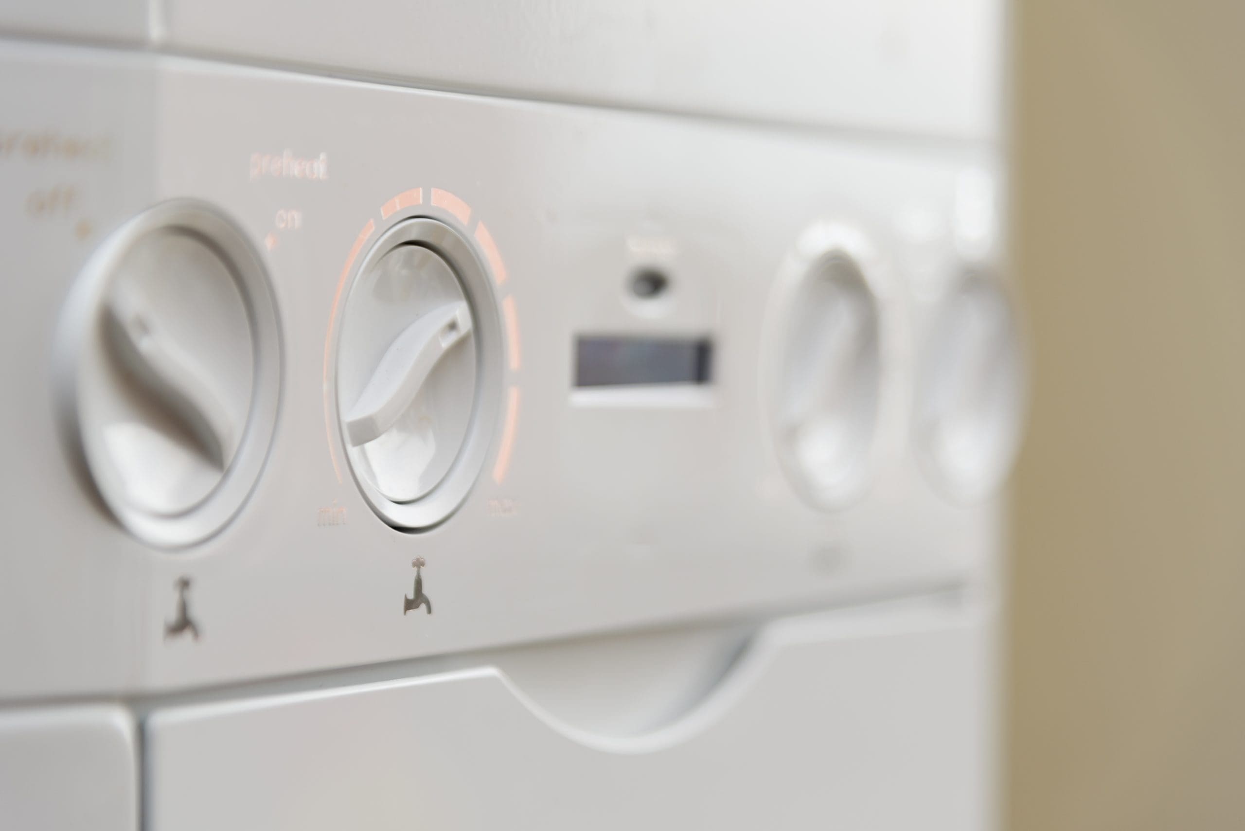 Close-up shot of the control panel on a washing machine, featuring several round dials with settings and indicators, including a partially visible display screen. The image is taken at an angle, highlighting the dials' edges.